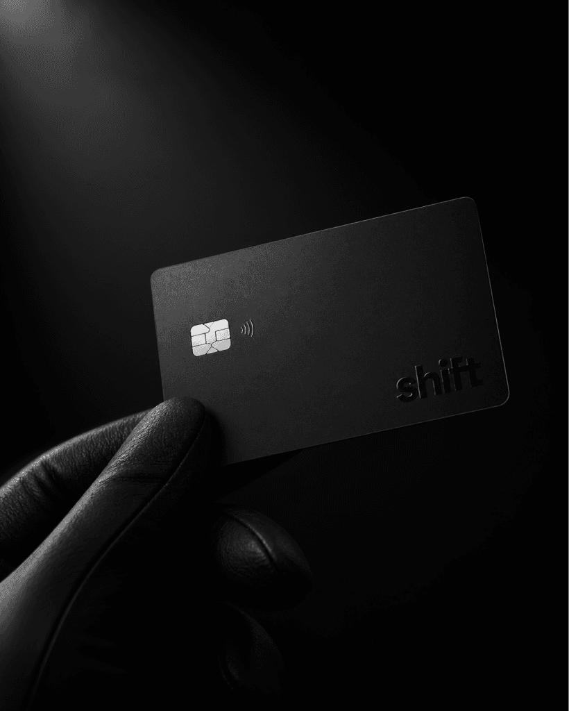 A gloved hand holding the matte black Carbon card against a dark background.